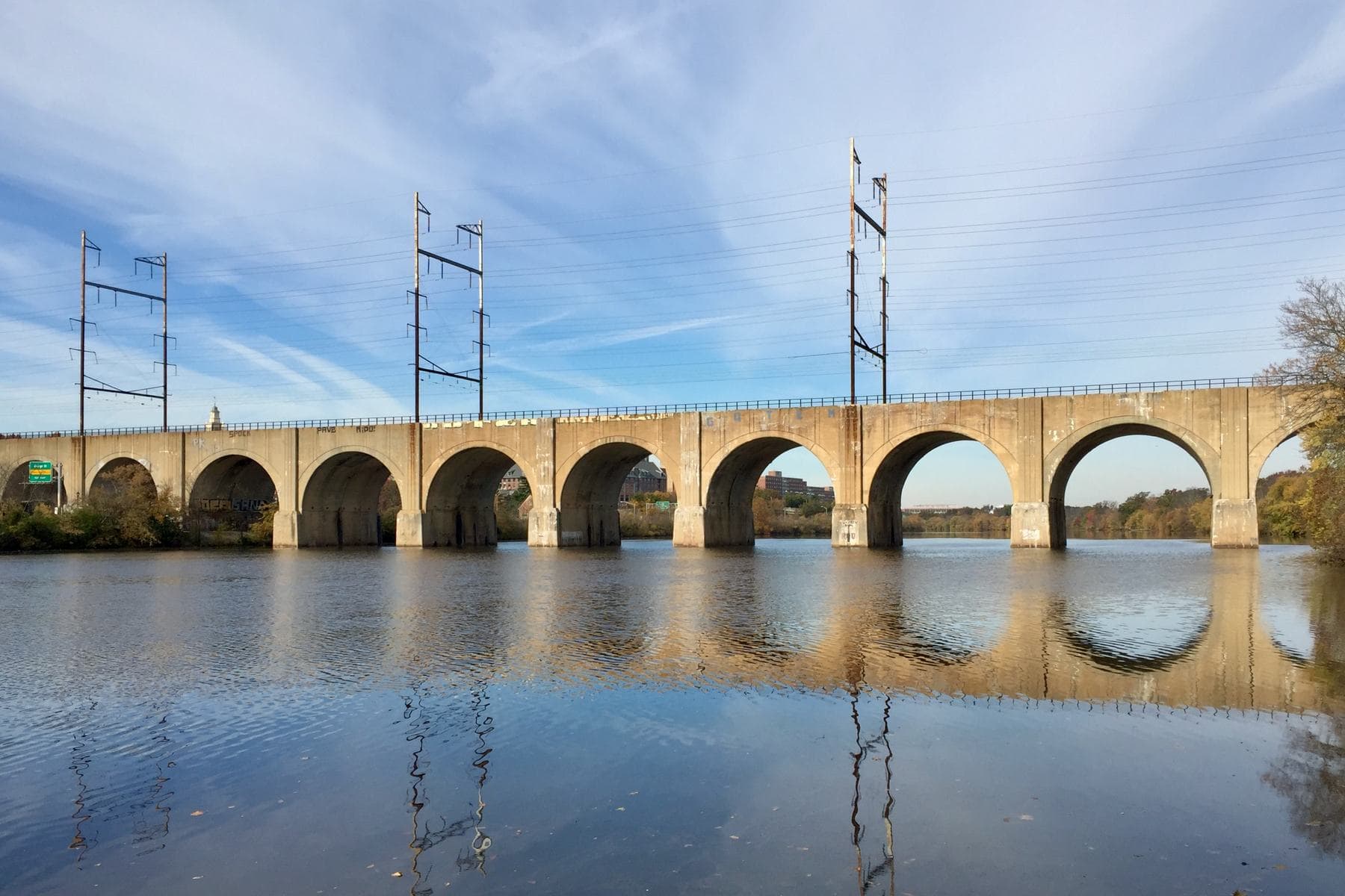 The arched stone railroad bridge over the Raritan River, reflected in the water on a clear autumn morning